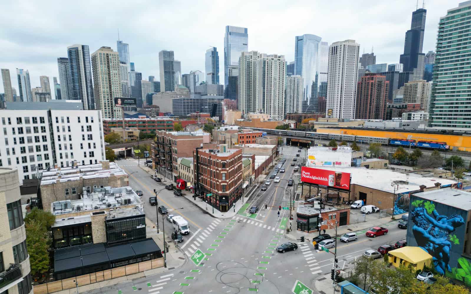 Overhead view of Grand/Halsted/Milwaukee Ave intersection in Chicago's River West, with city skyline in the background