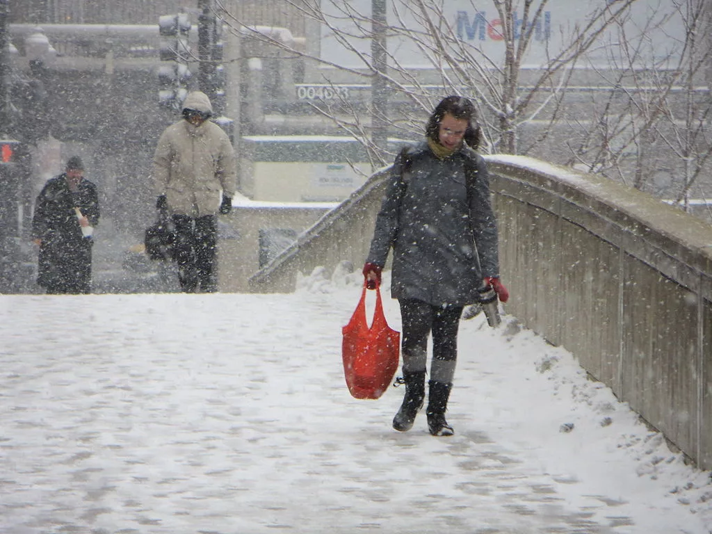 A woman walks through downtown Chicago with snow falling around her
